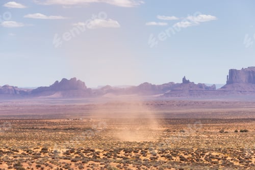 Preview: Dust Devil on a hot sunny day in a desert with red rocky mountains in background