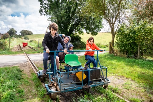 Preview: Family enjoying the rail bike attraction in France, Normandy. Father and sons on rail trolley.