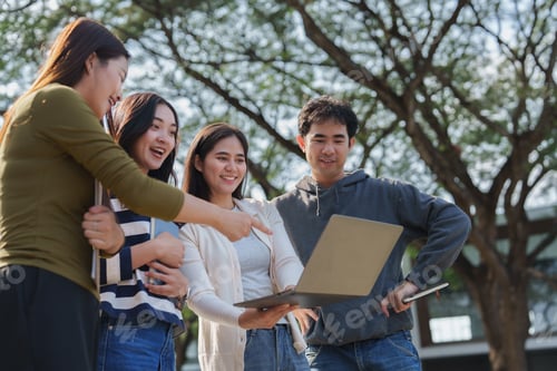 Preview: Group of university students collaborating on laptop outdoors