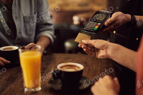 Preview: Close-up of woman paying with credit card in a cafe.