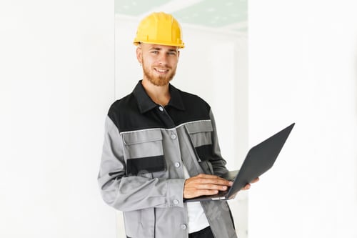 Smiling Worker Uses Laptop During Building Renovation