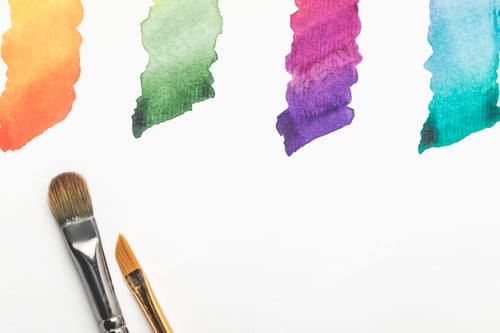 Preview: close-up view of paintbrushes and colorful bright paint strokes isolated on white