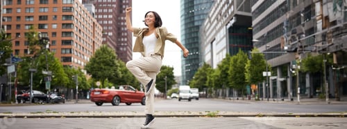 Preview: Portrait of asian happy girl jumping and dancing in city centre, posing on streets, express joy and