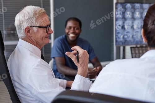Preview: Senior Male Chief Physician Talking to Colleagues during Working Meeting at Medical Office