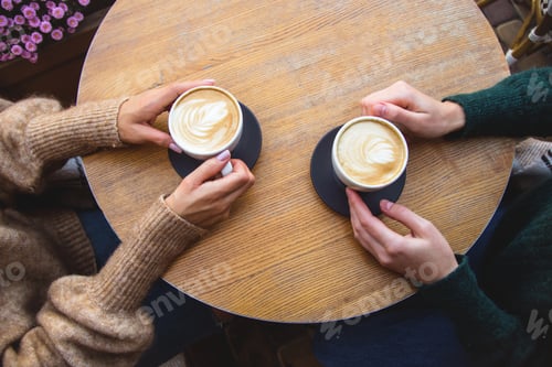 Preview: Two women drink coffee in the cafe terrace