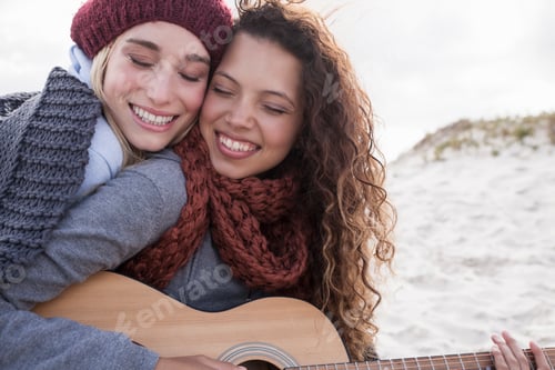 Preview: Portrait of two young female friends playing guitar at beach, Western Cape, South Africa