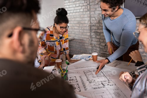 Preview: Group of modern business people in casual wear discussing architectural designs in the office.