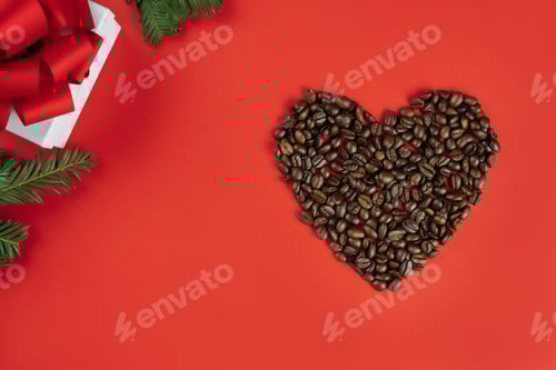 Preview: Brown coffee beans laid out in shape of heart with Christmas tree branches and gift box on red