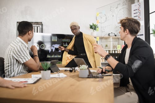 Preview: Team of multicultural male traders having negotiation at office room with modern gadgets