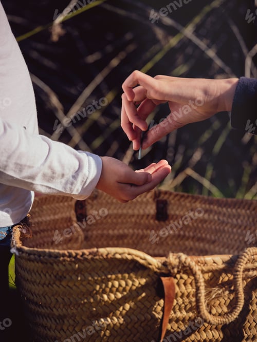 Preview: Crop woman putting piece of plastic into hand of boy