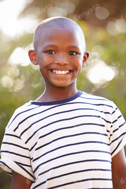 Preview: Smiling young black boy looking away from camera outdoors