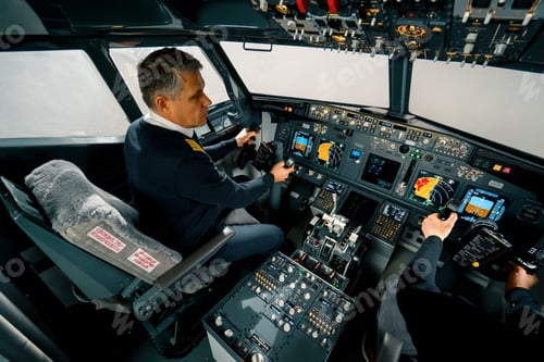 Preview: An experienced pilot instructs a young student before a training flight in the cockpit simulator
