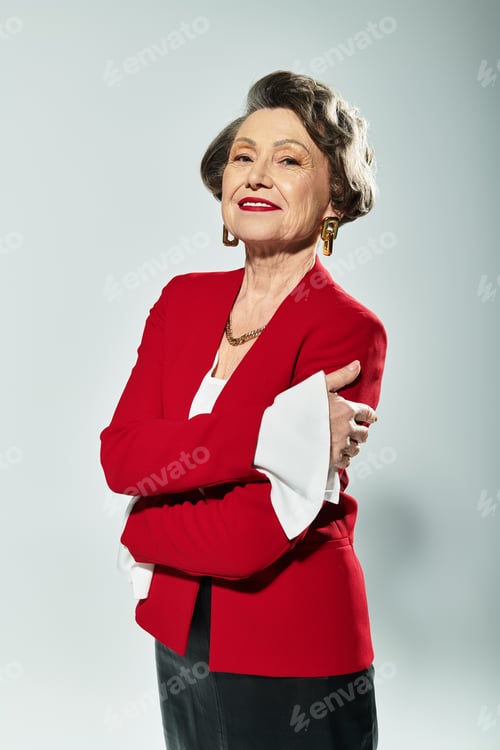 Preview: A stunning mature woman showcases her fashion sense in elegant attire against a grey backdrop.