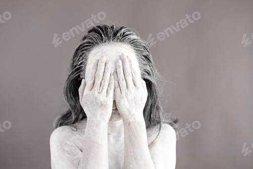 Preview: Art portrait of asian woman covered in clay isolated over grey background. Woman face like cracked p