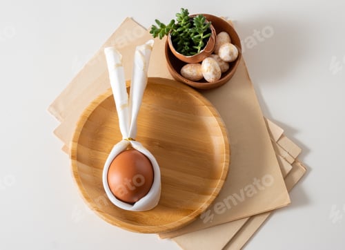 Preview: Top view flat lay egg with bunny ears on wooden plate serving for easter celebration.