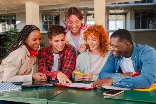 Preview: Diverse group of college teenage students studying together, looking at notes and using a cellphone