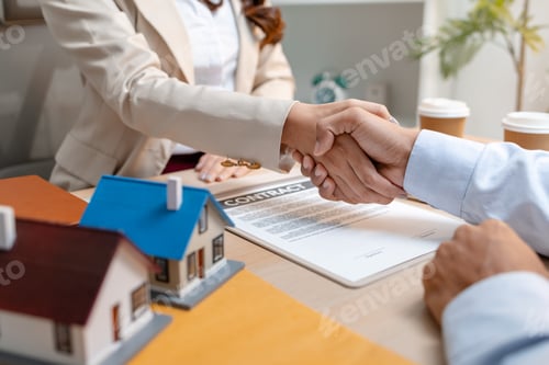 Preview: A real estate agent and a client are shaking hands after signing a house purchase agreement.