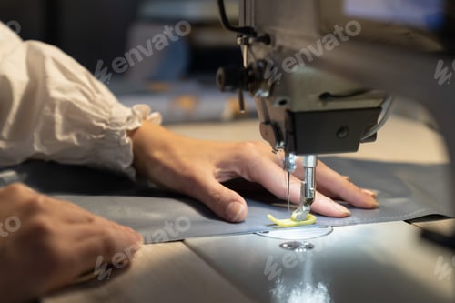 Preview: Closeup of female tailor work on sewing machine stitch fabric patterns for clothes. Garment industry