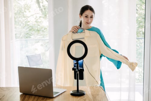 Preview: Fashion influencer showcasing yellow blouse with ring light and laptop, online content creation