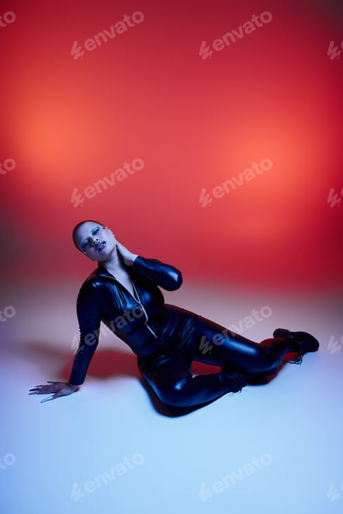 Preview: A young woman with short pink hair confidently poses in a vibrant studio