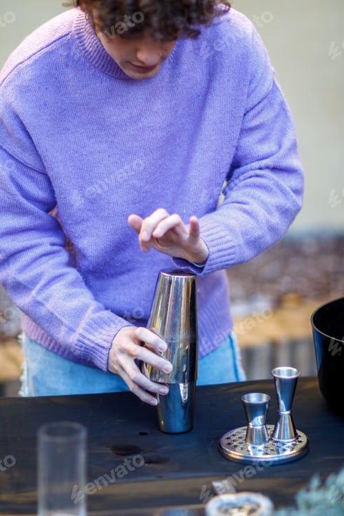 Preview: caucasian young red hair professional barista closing cocktail mixer to tap before start to shake it
