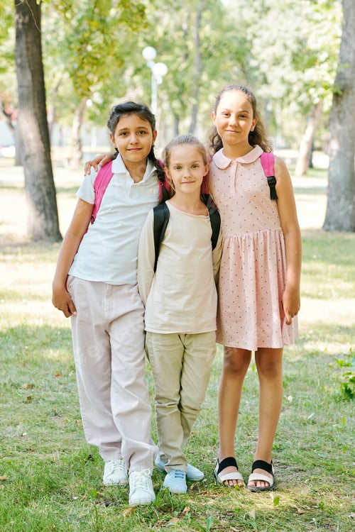 Preview: Three schoolgirls embracing in park