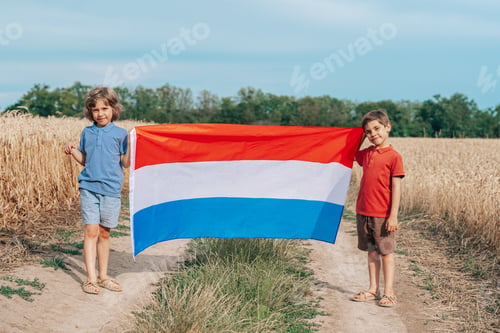 Preview: Children Standing With Flag Of Netherlands On Open Wheat Road Field.Happy Future