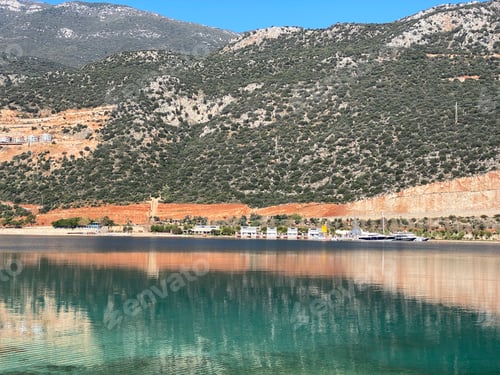 Preview: Serene mountain landscape reflected in clear blue lake with distant shoreline and sky