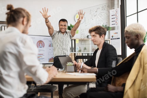 Preview: African man standing near big monitor and glass flip chart with raised hands celebrating success