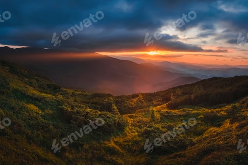 Preview: Mountain hill with stormy sky and sunbeam at sunset