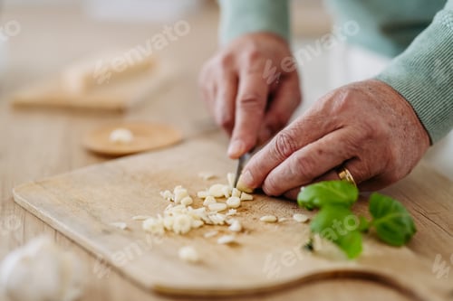 Preview: Close up of senior man cutting garlic.