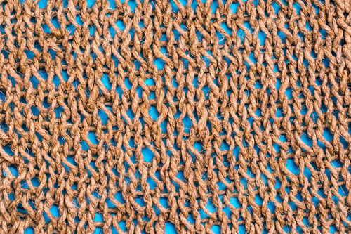 Preview: Knitted fabric from twine on a blue background.