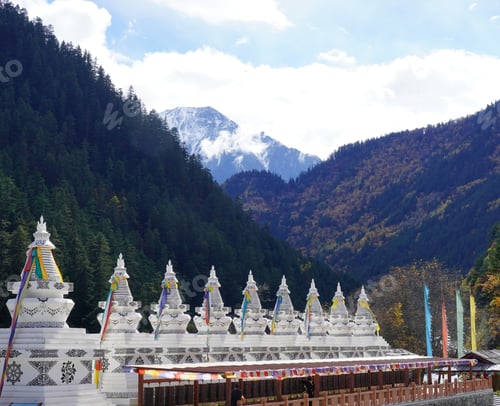 Preview: View of Tibetan stupas in a mountain valley with snow-capped peaks and lush forests.