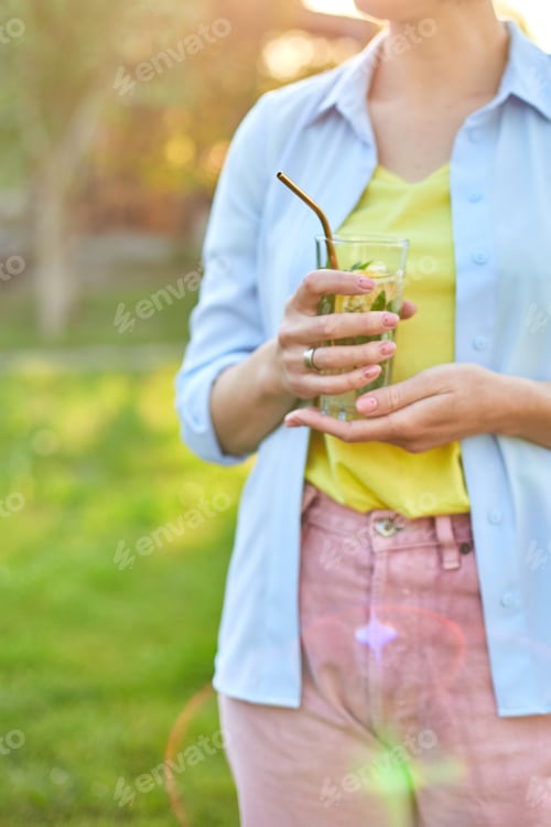 Preview: Woman Holds Refreshing Drink Outdoors on Sunny Day