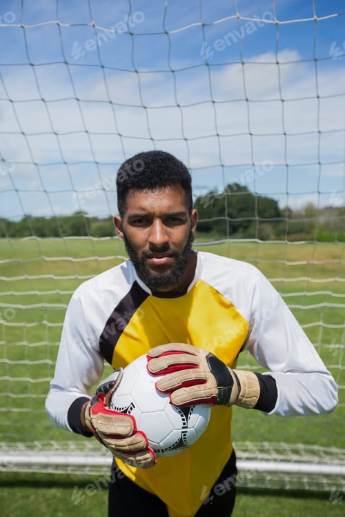 Preview: Goalkeeper holding football in front of goal post