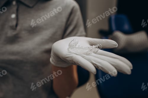 Preview: Gloved Hand Holds Clear Plastic Dental Straightener