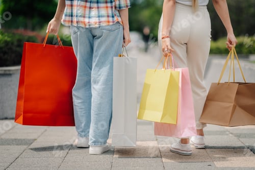 Preview: Women holding shopping bags walking away after purchases