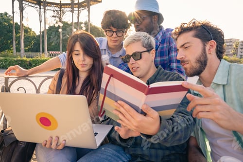 Preview: Diverse group of students collaborating with a laptop and tablet on a park bench.