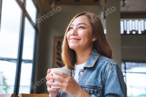 Preview: Portrait image of a young asian woman holding and drinking hot coffee in cafe