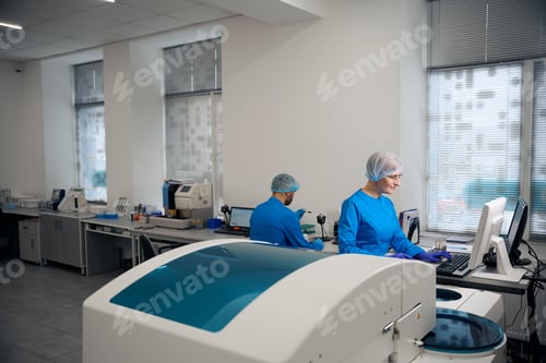 Preview: Man and woman laboratory technicians use high-tech equipment at work