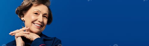 Preview: A graceful woman in her 60s models her stylish outfit against a striking blue backdrop, banner
