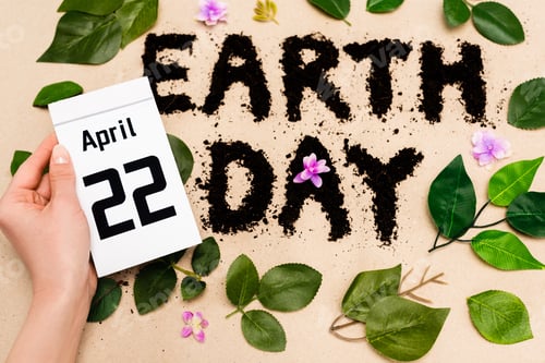 Preview: Cropped view of woman holding calendar with 22 april inscription near earth day lettering on beige