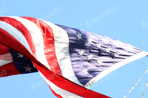 Preview: Low angle shot of a large American flag waving in a blue sky