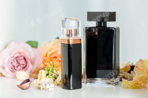 Vista previa: Two black perfume bottles with flowers on a table in a soft light setting