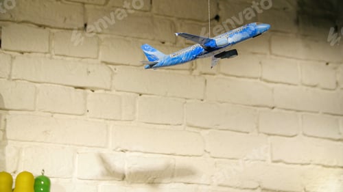Preview: Homemade airplane in the room. On the background of stone wall hanging toy airplane on a rope, the