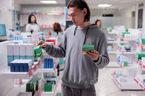 Preview: Male asian customer examining supplements on shelves