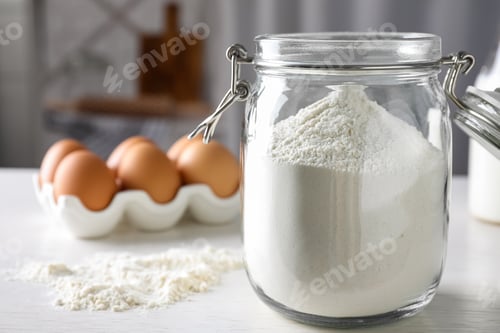 Preview: Glass jar with flour on white table indoors, closeup. Space for text