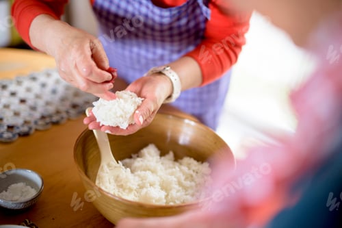 Preview: Close up of woman standing at a table in a kitchen, making sushi.
