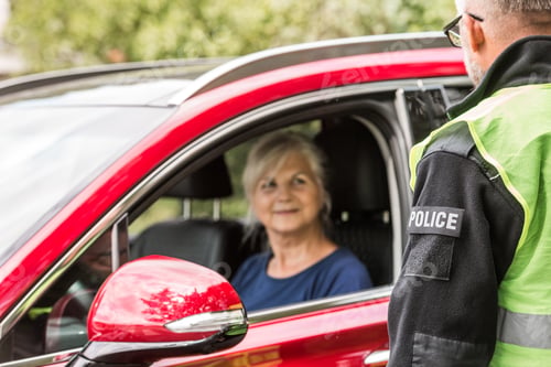 Preview: Policeman talks to an elderly lady sitting in a luxurious red car