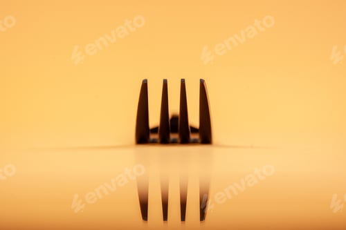 Preview: Top view of four metal tines on golden color background with free space